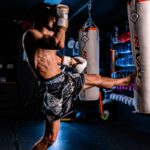 Man practicing muay thai kickboxing with a heavy bag.