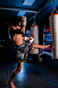 Man practicing muay thai kickboxing with a heavy bag.